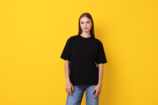 Woman wearing stylish black t-shirt on yellow background - Powered by Adobe