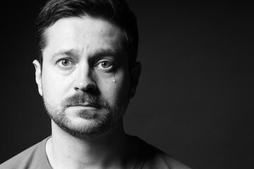 Sad man crying on dark background, space for text. Black and white effect