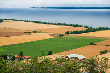 Vast farmland landscape with lake and cloudy sky.