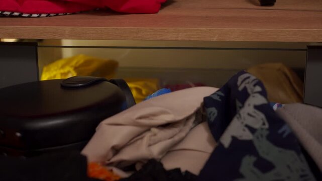 A close-up view reveals an open drawer showcasing a folded houndstooth patterned fabric, alongside other clothing items and a vibrant red garment. The scene captures organized apparel