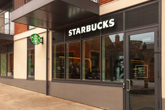 Starbucks logo on a facade of the modern residential building next to Starbuck cafe. Starbucks store with a sign.