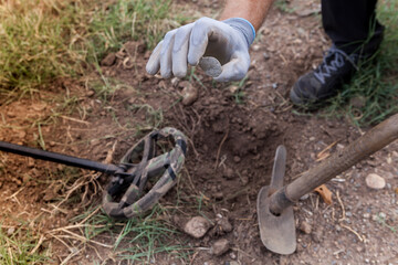 A man's hand with a metal detector holds a found buckle.