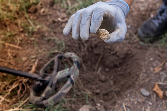 A man's hand with a metal detector holds a found buckle.