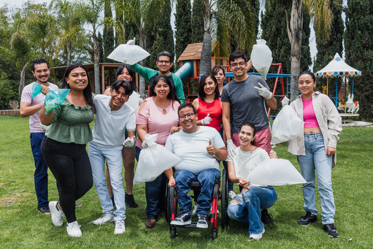 Group of diverse Latin people collecting trash in a public park in Mexico, Latin America. Group of multi age Hispanic volunteers cleaning up and collecting plastic in save the planet concept