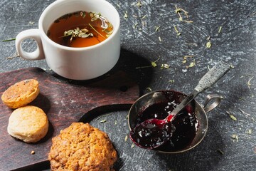 Still life - blueberry jam and herbal tea on the table. Sweet food on a dark background