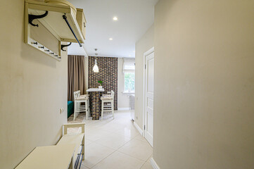 Cozy interior with hallway view, leading to a compact dining area featuring brick accents and bar stools