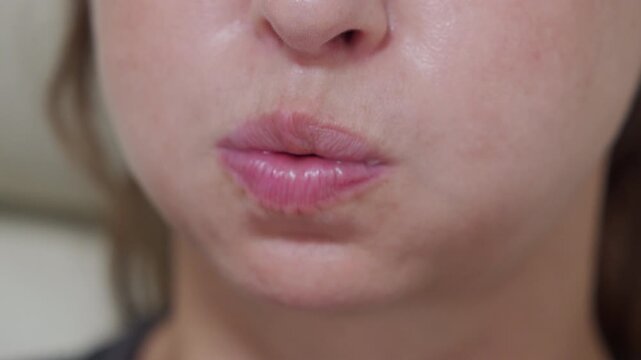 a woman puffing out her cheeks and blowing air, showcasing the facial expression and action.