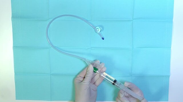 Close-up video of inflating the balloon of a urinary catheter with a syringe in a sterile medical procedure