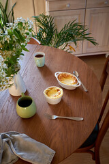 Cottage cheese souffle. Side view. A flowering branch in a vase. Souffle in a ramekin .