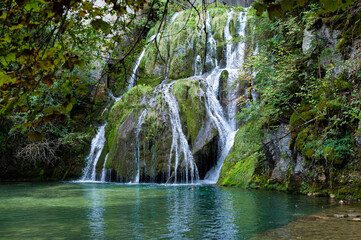 A magnificent waterfall in the middle of the forest in the Jura Mountains in France. In this region, the karstic terrain is conducive to beautiful waterfalls with clear, cool water.