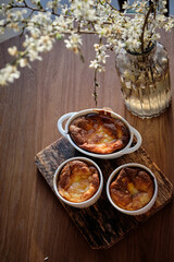 Cottage cheese souffle. Side view. A flowering branch in a vase. Souffle in a ramekin .