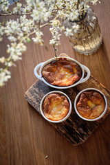 Cottage cheese souffle. Side view. A flowering branch in a vase. Souffle in a ramekin .