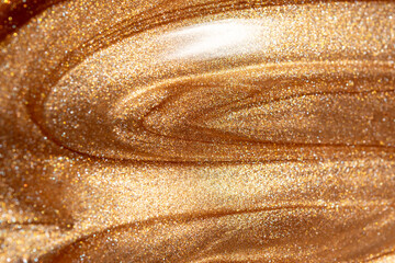 Texture background with golden shimmering cosmetic body spray or gel. Glowing backdrop.