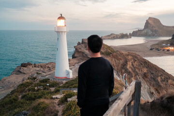 Castlepoint Lighthouse with male tourist looking on coastline in New Zealand