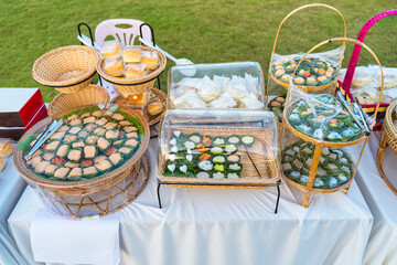 Assorted Thai traditional desserts in wooden basket and tray on outdoor event celebration