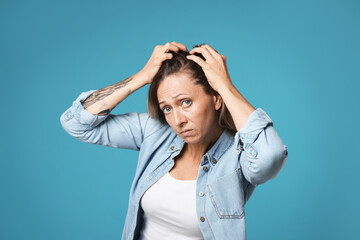 Worried woman with hair loss problem on light blue background