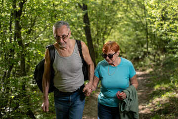 Senior couple hiking together in vibrant forest smiling and enjoying nature outdoors.