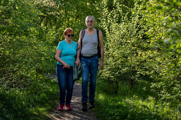 Happy senior couple walking through lush green forest enjoying outdoor hiking adventure