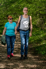 Senior couple hiking happily in green forest enjoying nature and outdoor adventure