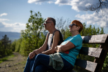 Senior couple sitting on bench enjoying peaceful view of nature together