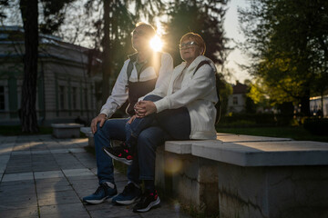 Senior couple sitting in park at sunset enjoying retirement and traveling.