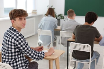 Fototapeta premium Students taking exam at wooden table indoors, selective focus