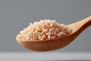 Close-up of Raw White Rice Grains in Wooden Spoon on Gray Background