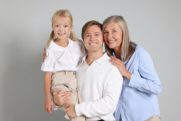 Senior woman with her son and granddaughter on light background