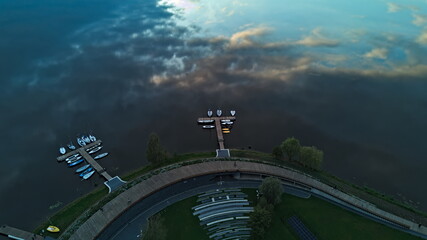 Aerial view of wooden pier with boats on calm reflective water