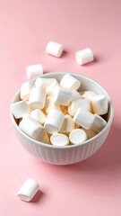 White marshmallows in a bowl against a pink background