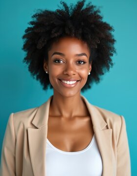 Portrait of smiling Black woman with afro hair wearing beige jacket and white top against blue background. Studio shot for ID, business, or resume.