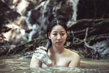 Serene Portrait of a Young Woman in Natural Water Pool Surrounded by Lush Greenery, Embracing...