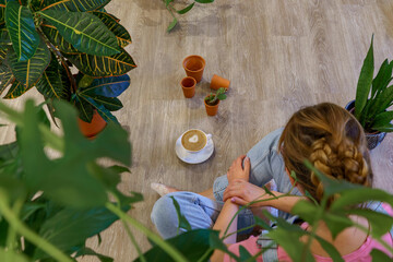 A woman surrounded by several houseplants. 