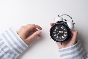 Woman holds an alarm clock. It's time to get up, time for morning rituals. 