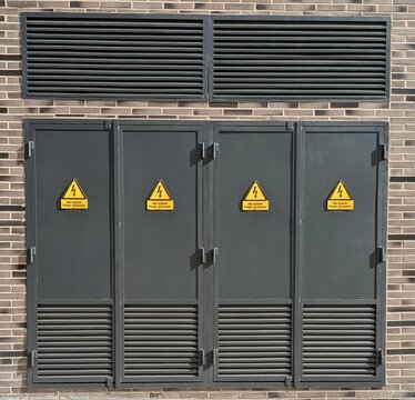 Estaci&oacute;n el&eacute;ctrica de alta tensi&oacute;n, con avisos de "Alto voltaje Peligro de muerte" en puertas met&aacute;licas y una rejilla superior de ventilaci&oacute;n en fachada de edificio 