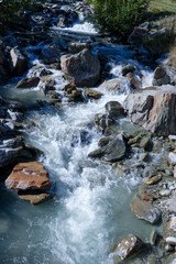 Flowing mountain stream with clear water cascading over rocks, surrounded by lush greenery and natural landscape, showcasing the beauty of nature and tranquility