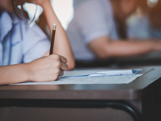 Students reading exam answer sheets exercises in classroom of school with headache and stress