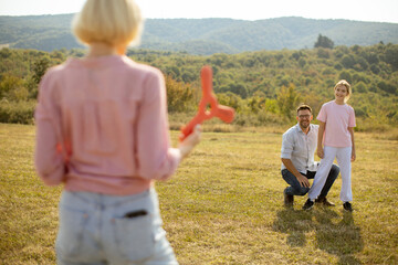 Family enjoys outdoor playtime with frisbee in a sunny green field during the afternoon