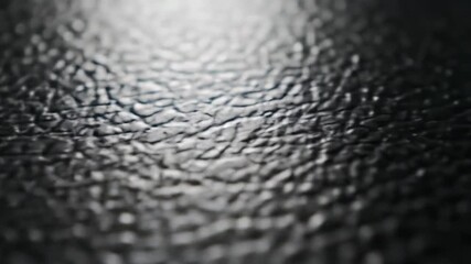 Detailed macro photograph of a dark, bumpy, and textured synthetic material surface with selective focus. - Powered by Adobe