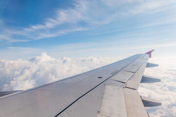 Fototapeta premium View from the airplane window at a beautiful cloudy sky and the airplane wing