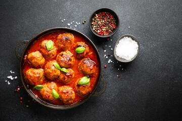 Meatballs in tomato sauce in iron plate on black background.