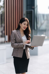 Fototapeta premium Confident Professional Engaged in Modern Work: An elegant professional woman, exuding confidence, focuses intently on her laptop.