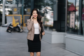 City Business Call: A dynamic woman on a call strides confidently through a bustling urban landscape, carrying a laptop and radiating a professional demeanor.