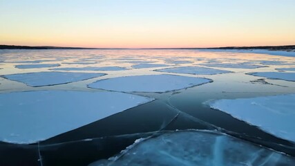 A gentle drone flyover captures a stark, geometric grid formed by fractured ice floes drifting on a partially frozen, serene lake at dawn unique, winter, wilderness - Powered by Adobe