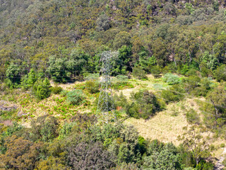 Drone aerial photograph of an electrical transmission tower running through regional bushland in the Blue Mountains in NSW, Australia.