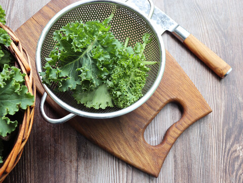 Fresh green curly kale leaves on a wooden table.