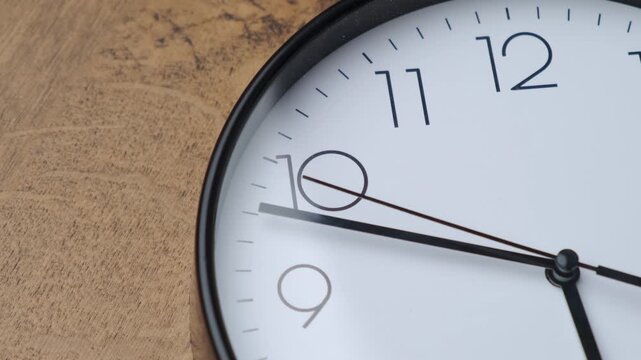 A close-up view of a minimalist clock design, showcasing its elegant features against a wooden backdrop.