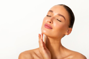 Beautiful woman with perfect face and closed eyes touching chin, lady with glowing hydrated facial...