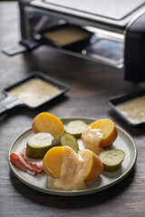Delicious traditional Swiss melted raclette cheese on diced boiled or baked vegetables served in individual skillets