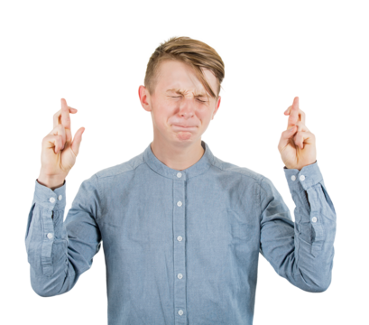 Strained teenage guy stands concerned with eyes closed and clenched teeth, crossing fingers in hope of good luck. Young man adolescent, isolated portrait, praying for positive news